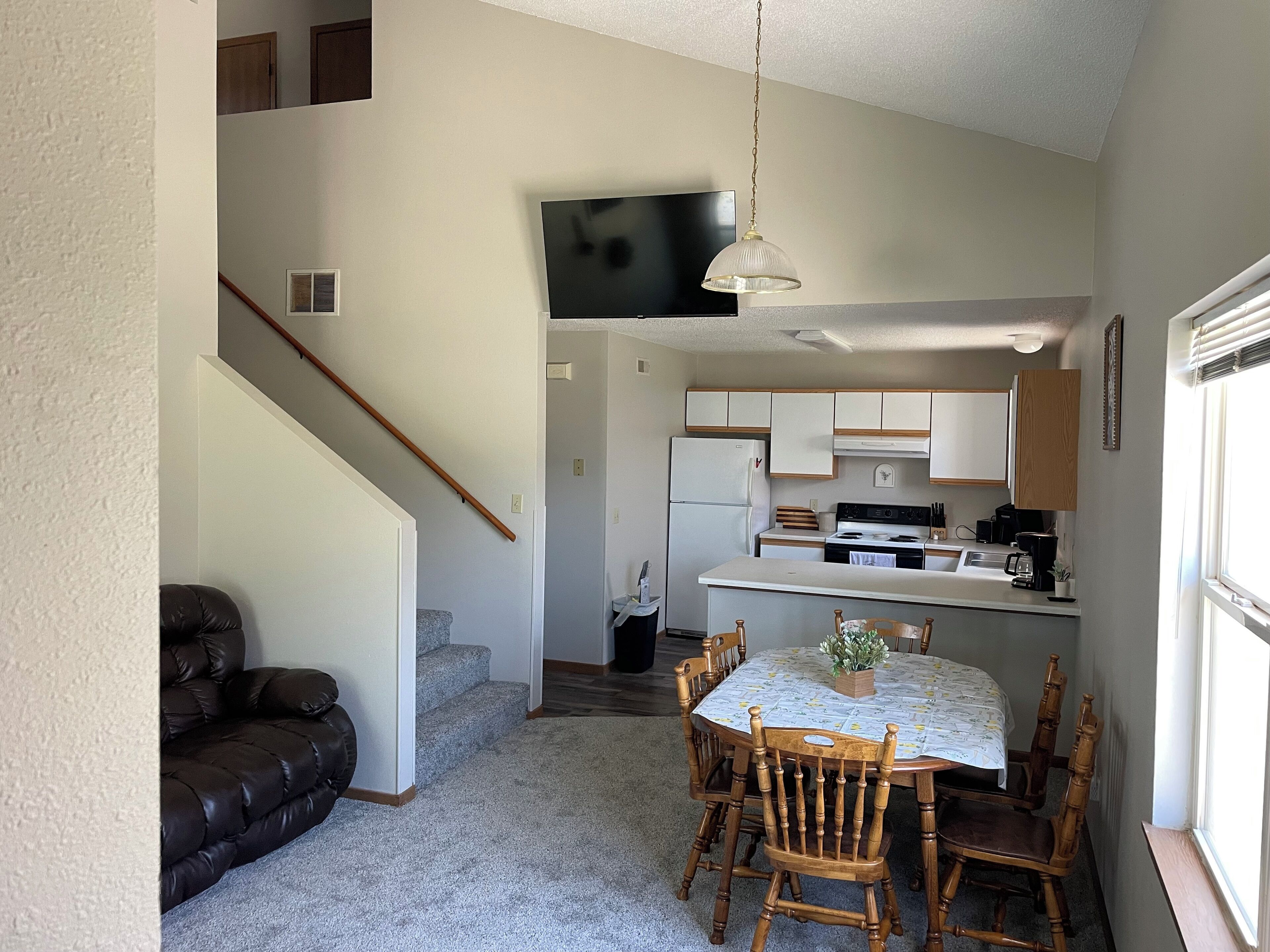 Cocina compacta con comedor, una escalera y una sala de estar con sofá de cuero.