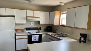 Una cocina moderna con armarios blancos, una estufa, un fregadero y una cafetera.