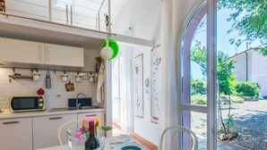 A dining area with a table set for two, a wine bottle, and a view of a garden through a large window.