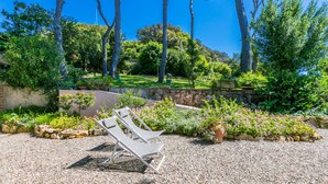 A garden with white lounge chairs and a stone wall.