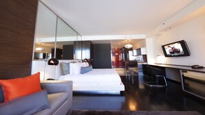 A modern hotel room with a bed, a desk, a chair, a TV, and a large mirror. - Resort in Las Vegas with NO RESORT FEES & FREE VALET SERVICE! (Las Vegas)