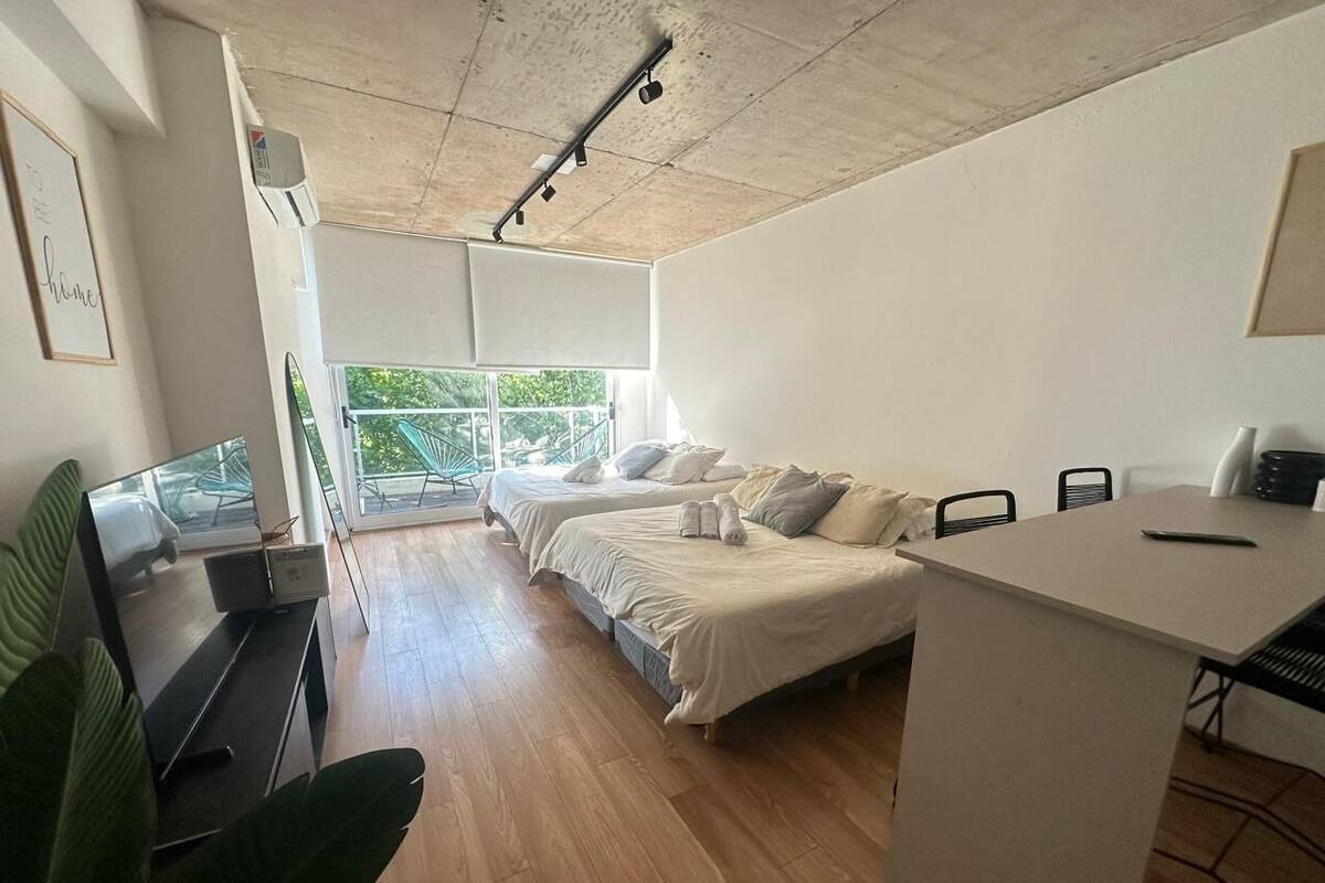 A modern room with a wooden floor, a bed, a desk, and a TV.