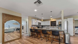 A modern kitchen with a central island, bar stools, and stainless steel appliances. - The Latham Abode | Spa | Firepit | Game Room | NEW (Joshua Tree)