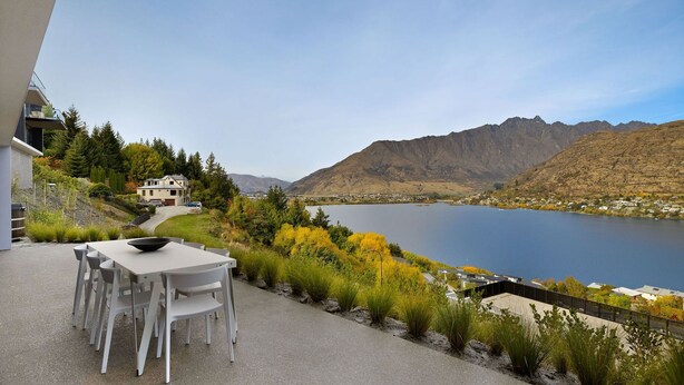 A patio with a table and chairs overlooking a lake and mountains. - The Bunker Charlie A-2 Bedroom (Queenstown)