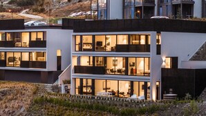 A modern multi-story building with large windows and balconies, featuring a mix of indoor and outdoor seating areas. - The Bunker Charlie A-2 Bedroom (Queenstown)