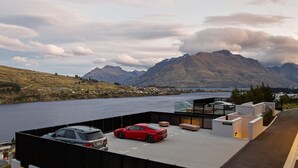 A rooftop parking area with two cars, a mountain view, and a lake. - The Bunker Charlie A-2 Bedroom (Queenstown)