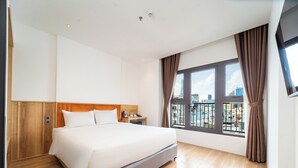 Habitación de hotel con una cama grande, paneles de madera, una mesita de noche, una ventana con cortinas y vistas a la ciudad.
