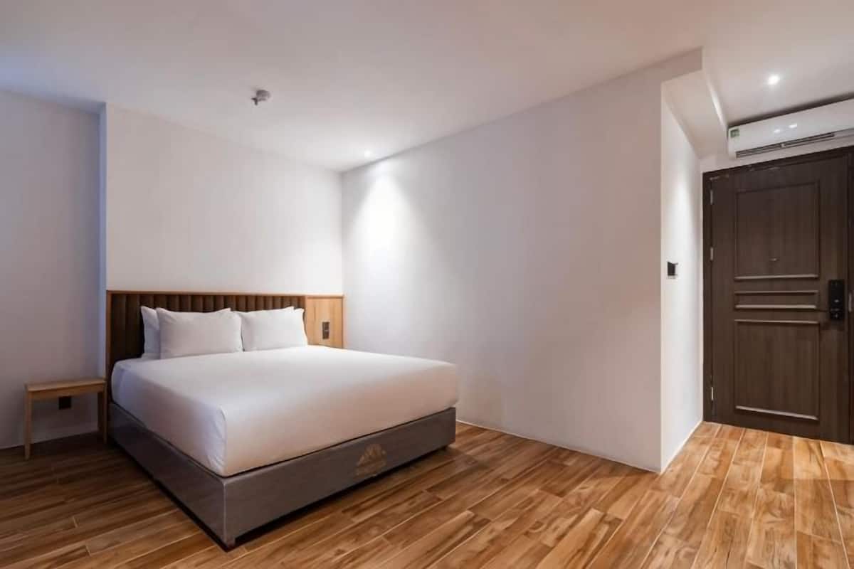 Un dormitorio con cama, suelo de madera, mesita de noche y armario.
