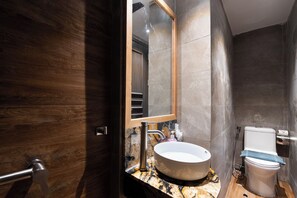 A modern bathroom with a wooden vanity, a marble countertop, a white sink, and a toilet. - Haven Hut Hotel - Ky Con (Ho Chi Minh City)