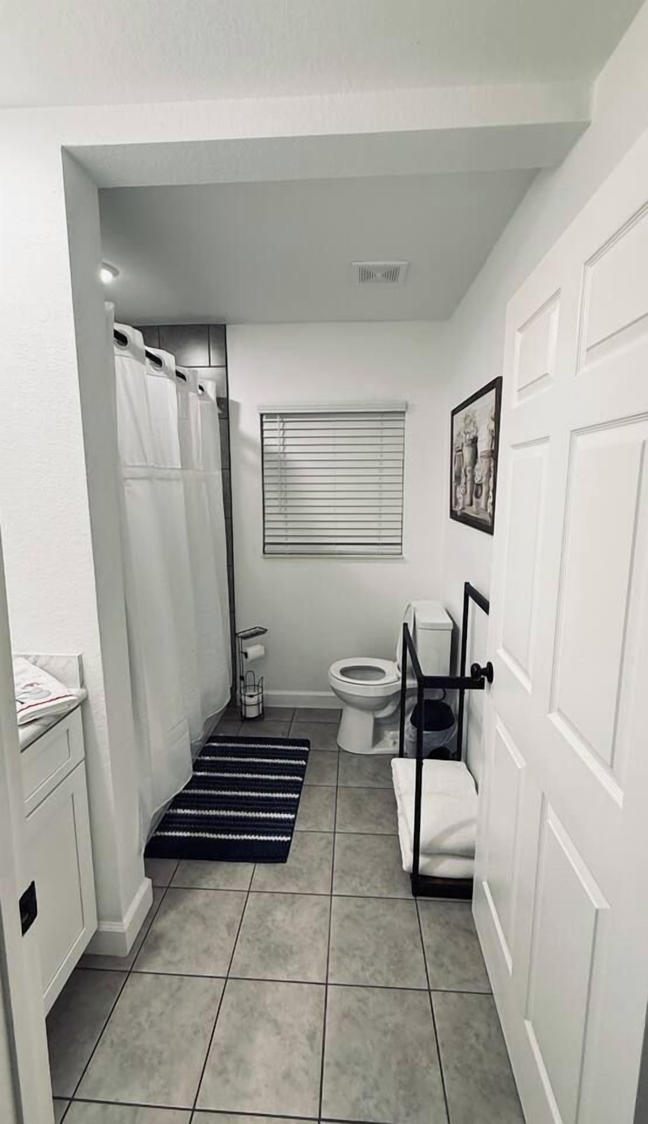 Une petite salle de bain comprenant une douche, des toilettes et une petite fenêtre.