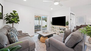Een moderne woonkamer met grijze banken, een flatscreen televisie en een plafondventilator.