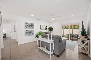 A modern living room with a grey sofa, white console table, and artwork on the walls.