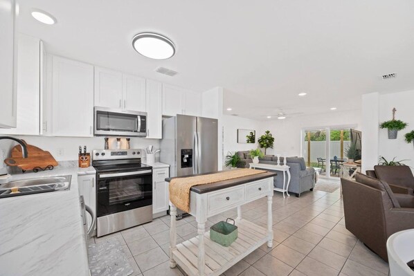 A modern kitchen with white cabinets, stainless steel appliances, and a central island.