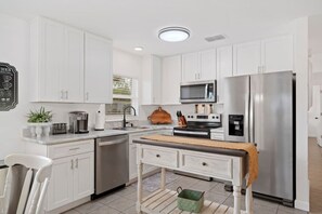 Une cuisine moderne avec des meubles blancs, des appareils en acier inoxydable et un îlot central.