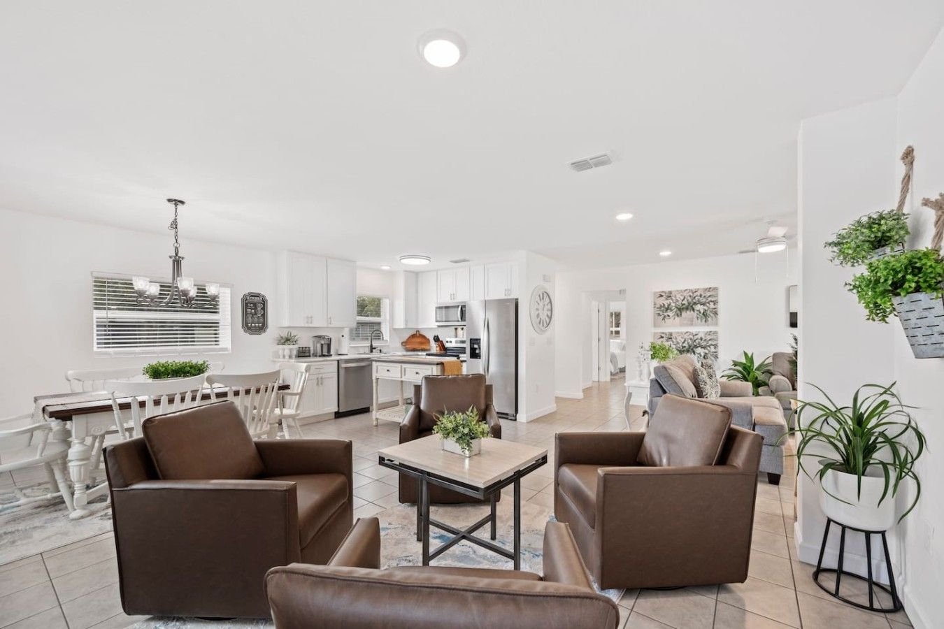 A modern living room with brown leather sofas, a dining table, and a kitchen in the background.