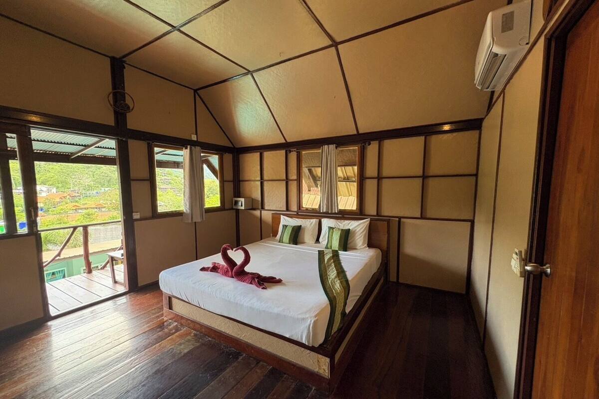 Une pièce spacieuse avec un grand lit, un plancher en bois et une vue sur l’extérieur.