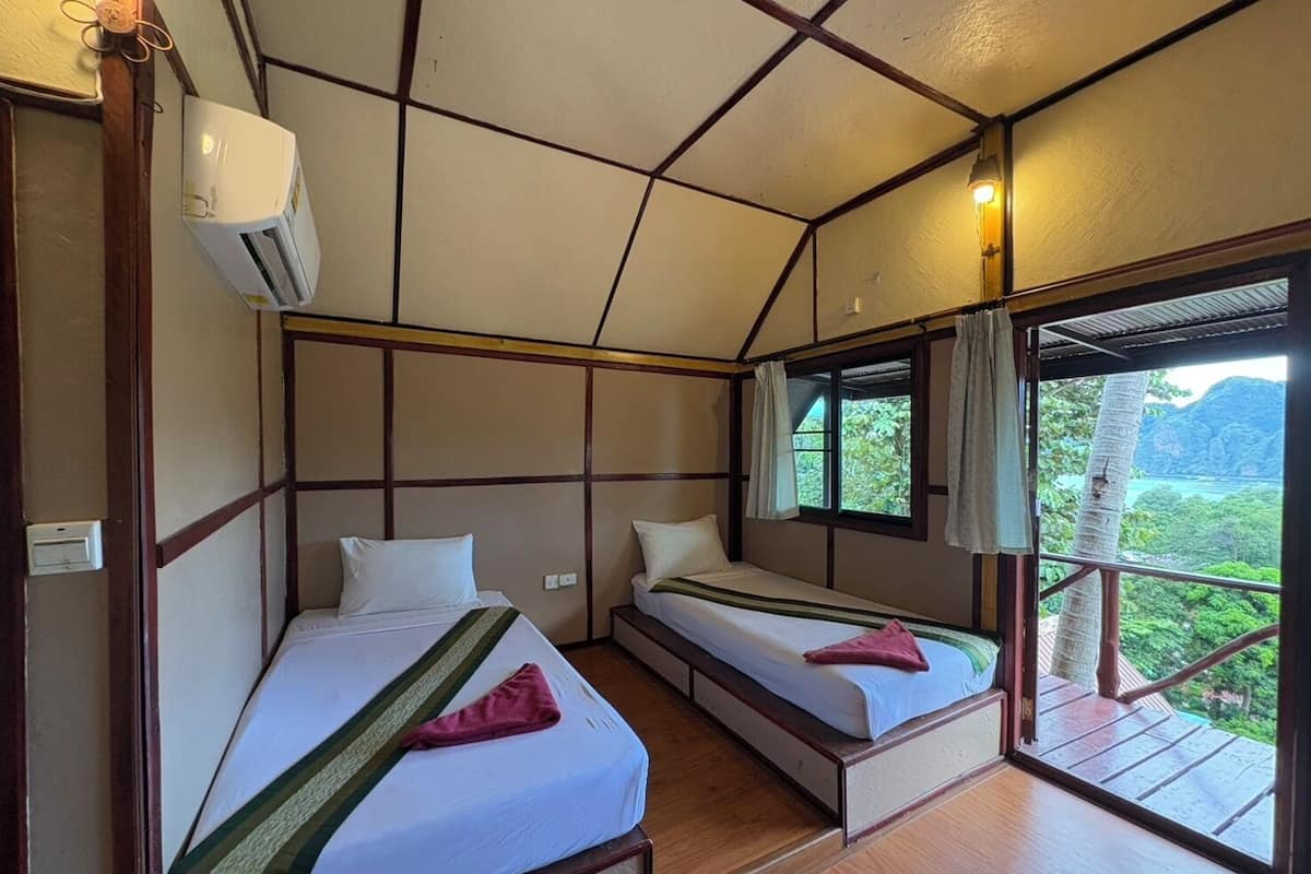 Une chambre avec deux lits, une fenêtre avec des rideaux et un appareil de climatisation.
