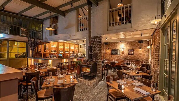 Un restaurante acogedor con chimenea de ladrillo, mesas de madera y una zona de bar.