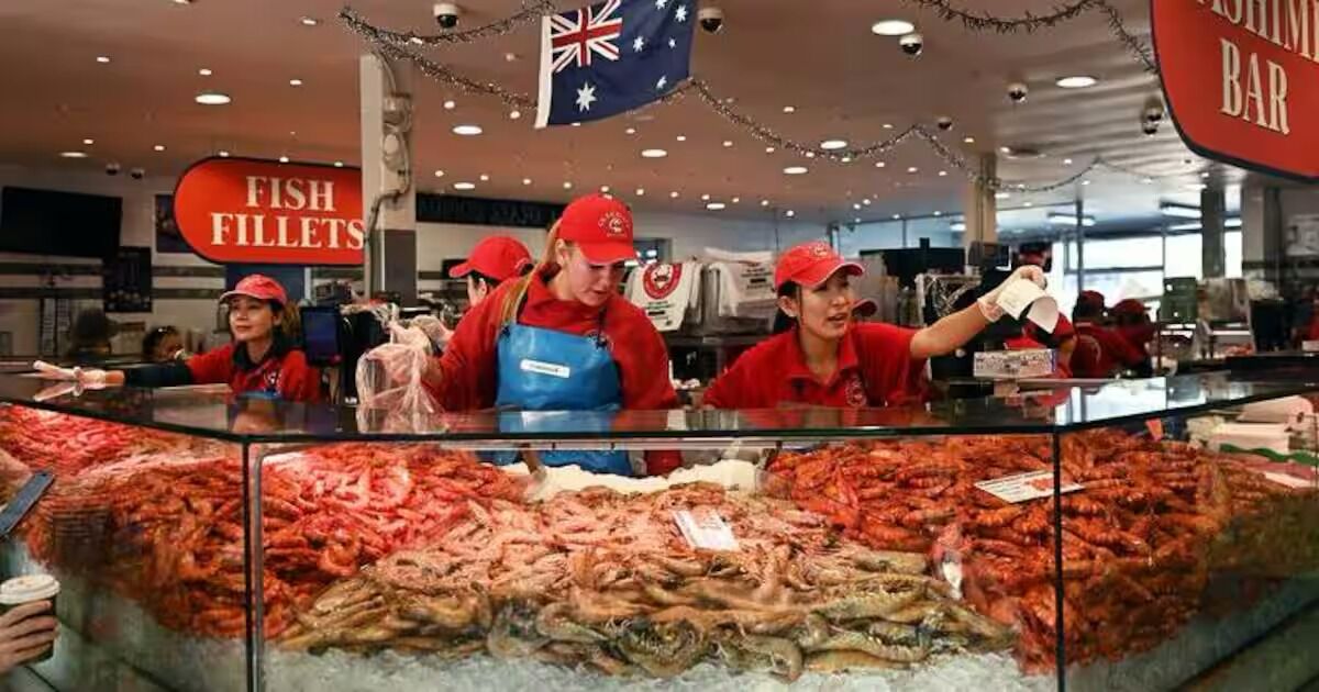 A seafood display with various types of fish and seafood, including prawns and fish fillets, in a store setting.