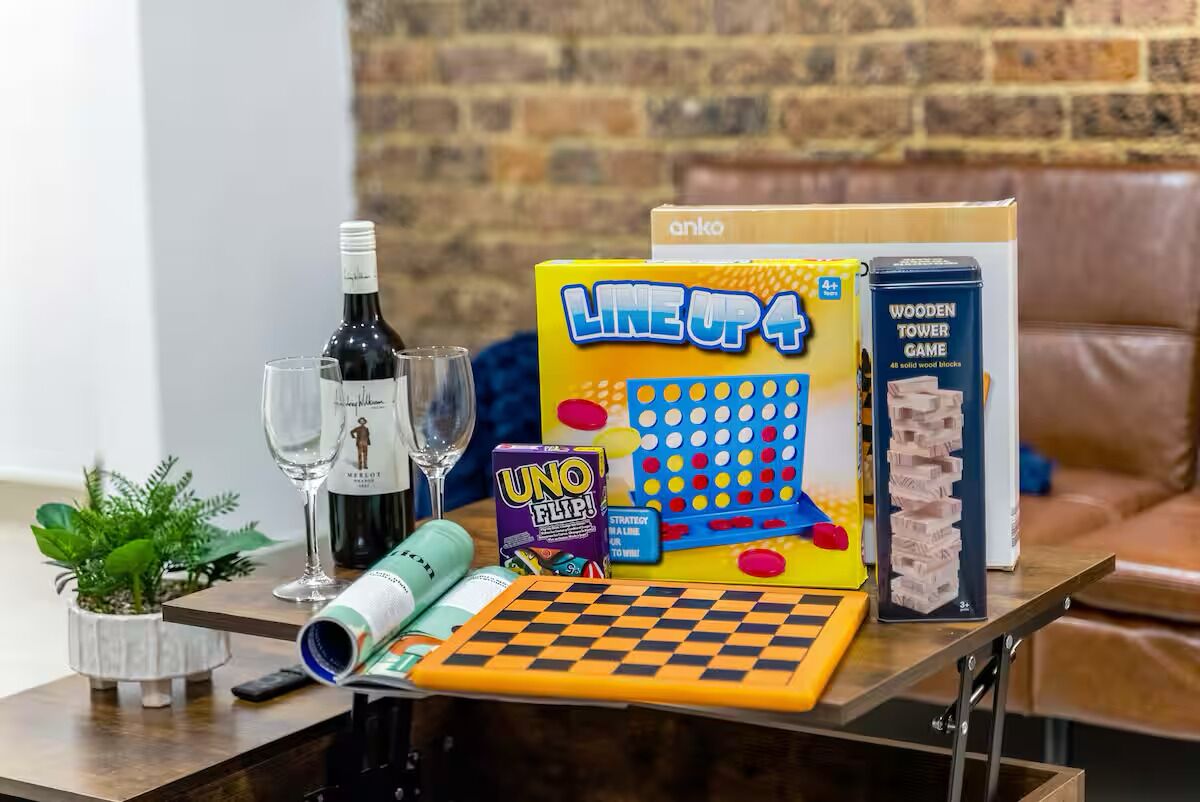 A table with board games, a wine bottle, glasses, and a small plant.