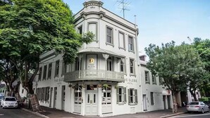 A historic building with a corner balcony, labeled "The Glebe Hotel," featuring classic architecture and a prominent year marker "1862" at the top.