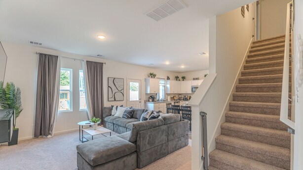 A spacious living room with a gray sectional sofa, a small coffee table, and a staircase leading to the upper floor. - Pool house with hot tub! (Houston)