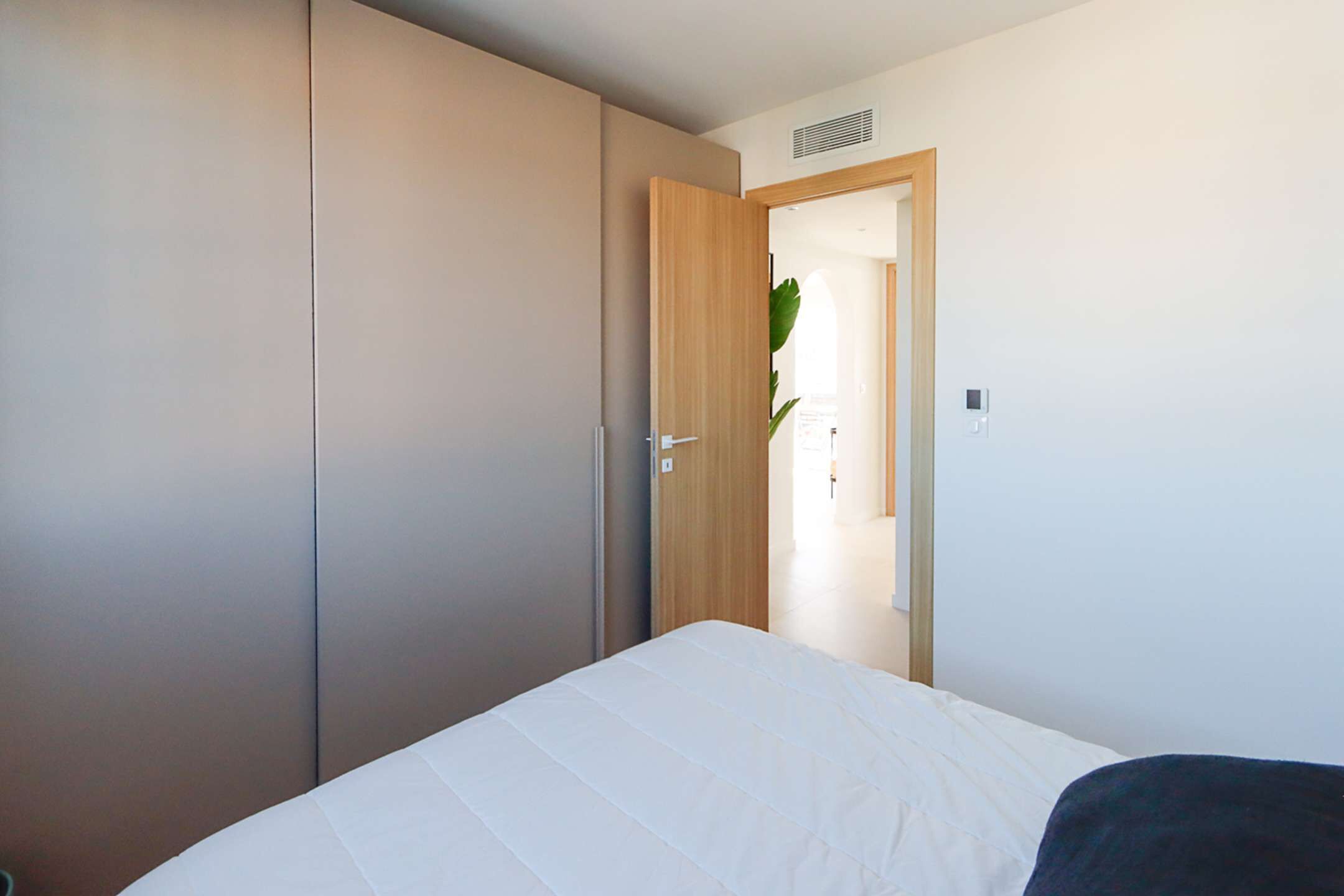 Ein Schlafzimmer mit Bett, Schrank und einer Tür zu einem anderen Raum.