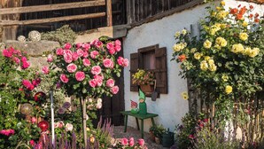 Un jardín con diversas flores y plantas, estructuras de madera y una pequeña mesa con figuritas.
