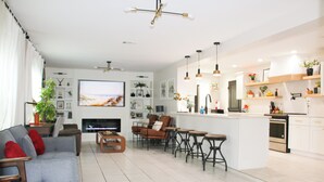 A modern living room with a grey sofa, red cushions, a TV, and a fireplace. - 3BR Open-Plan Retreat w/ Heated Pool, Screened Patio & Grill – Melbourne (Melbourne)