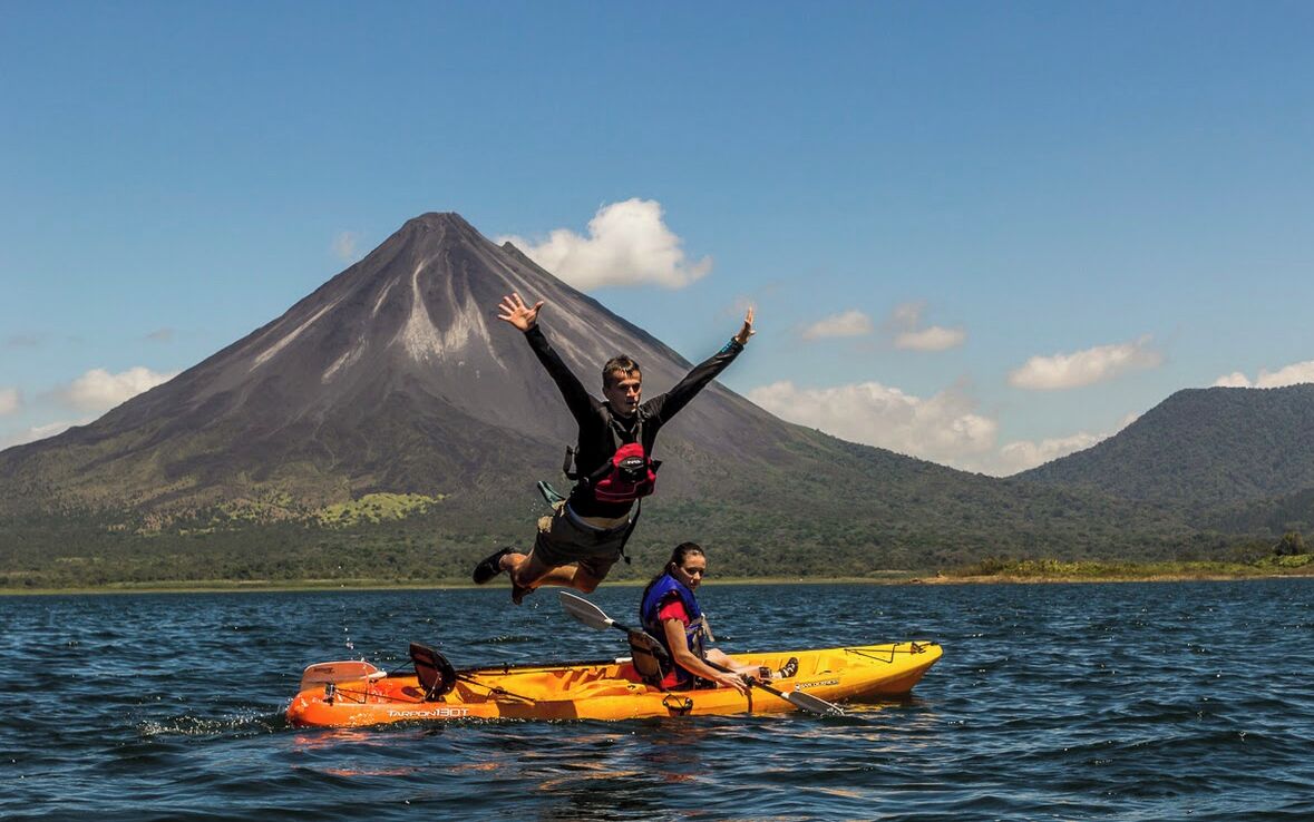 Une personne dans un kayak sur une étendue d’eau, avec une montagne en arrière-plan.