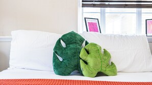 Una cama con almohadas blancas y una almohada verde con diseño de hoja.
