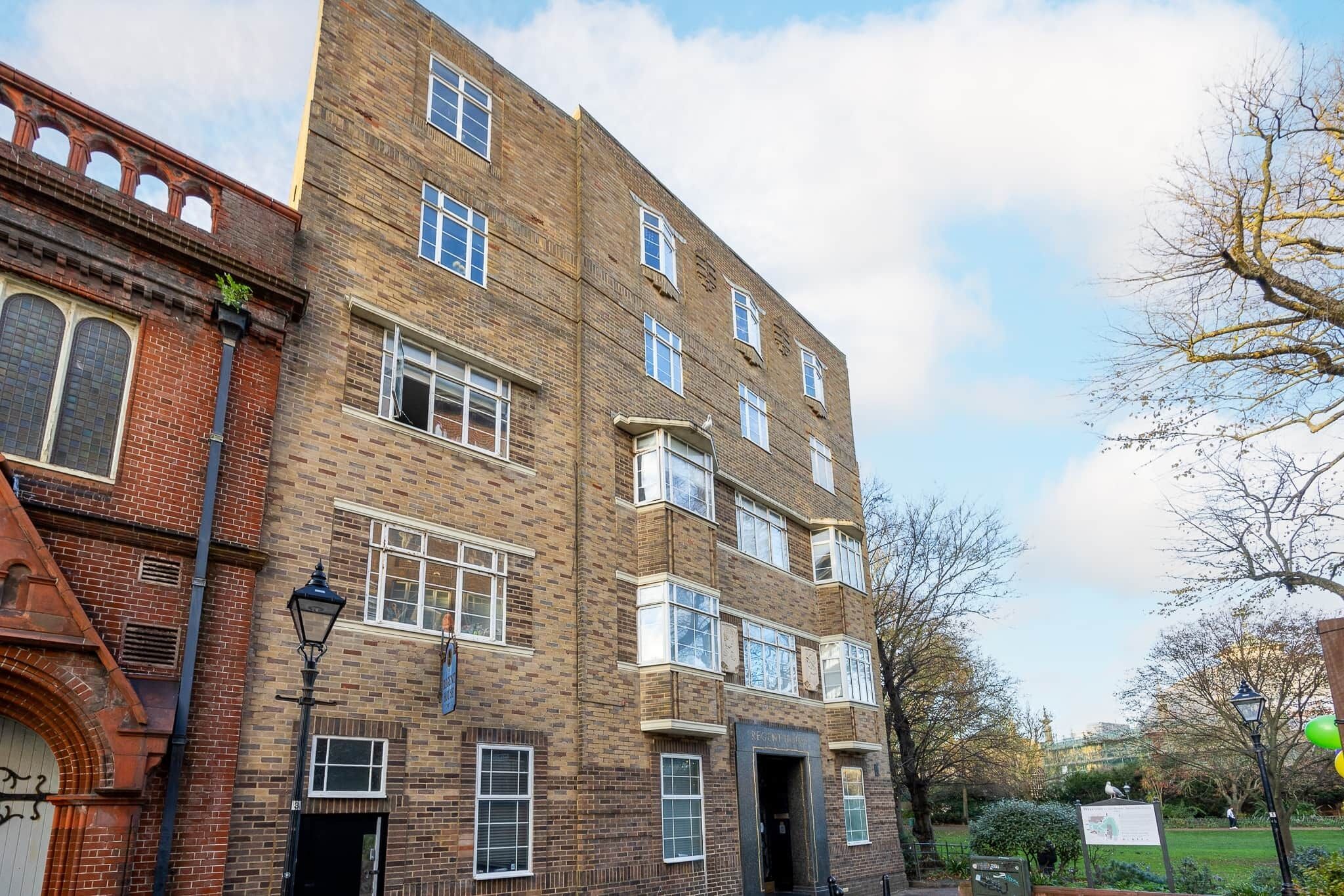 A multi-story brick building with multiple windows and a sign indicating it is a residential building.
