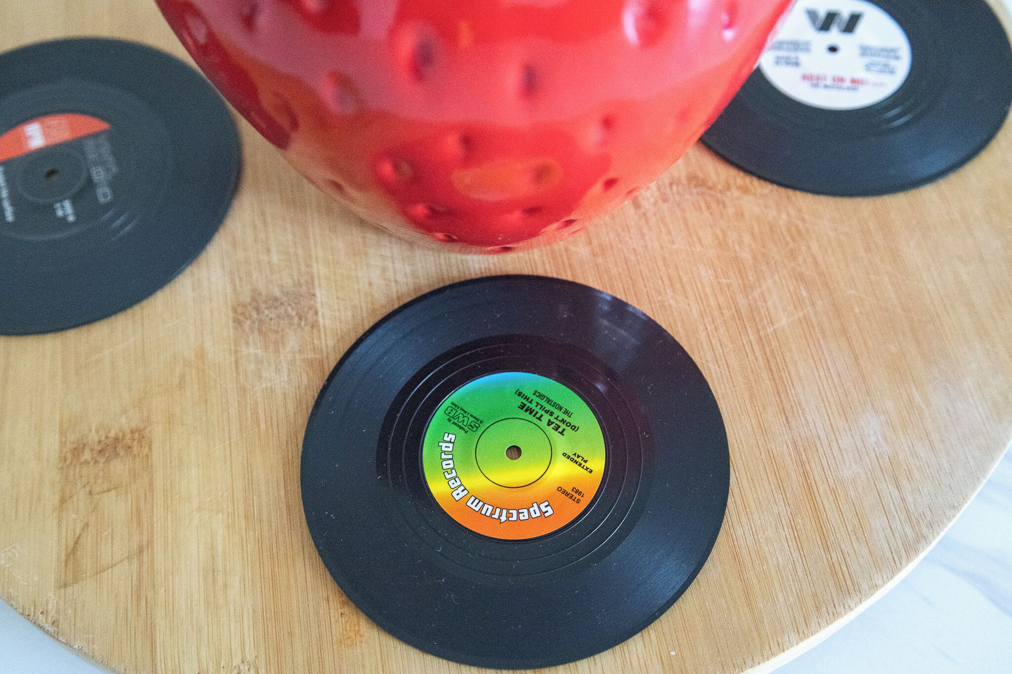 A wooden surface with three vinyl records and a red object.
