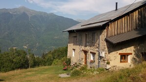 Un bâtiment rustique en pierre, doté d’un toit en pente, d’un revêtement extérieur en bois et d’un petit porche.