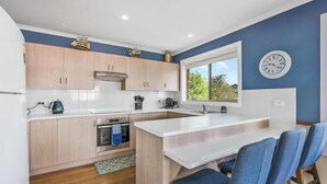 Una cocina moderna con armarios de madera, horno empotrado y ventana con vistas a la vegetación.