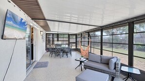 A sunroom with large windows, a dining area, and a seating area with a hammock. - Our Happy Place - super comfortable S Venice home close to beaches, shopping (Venice)