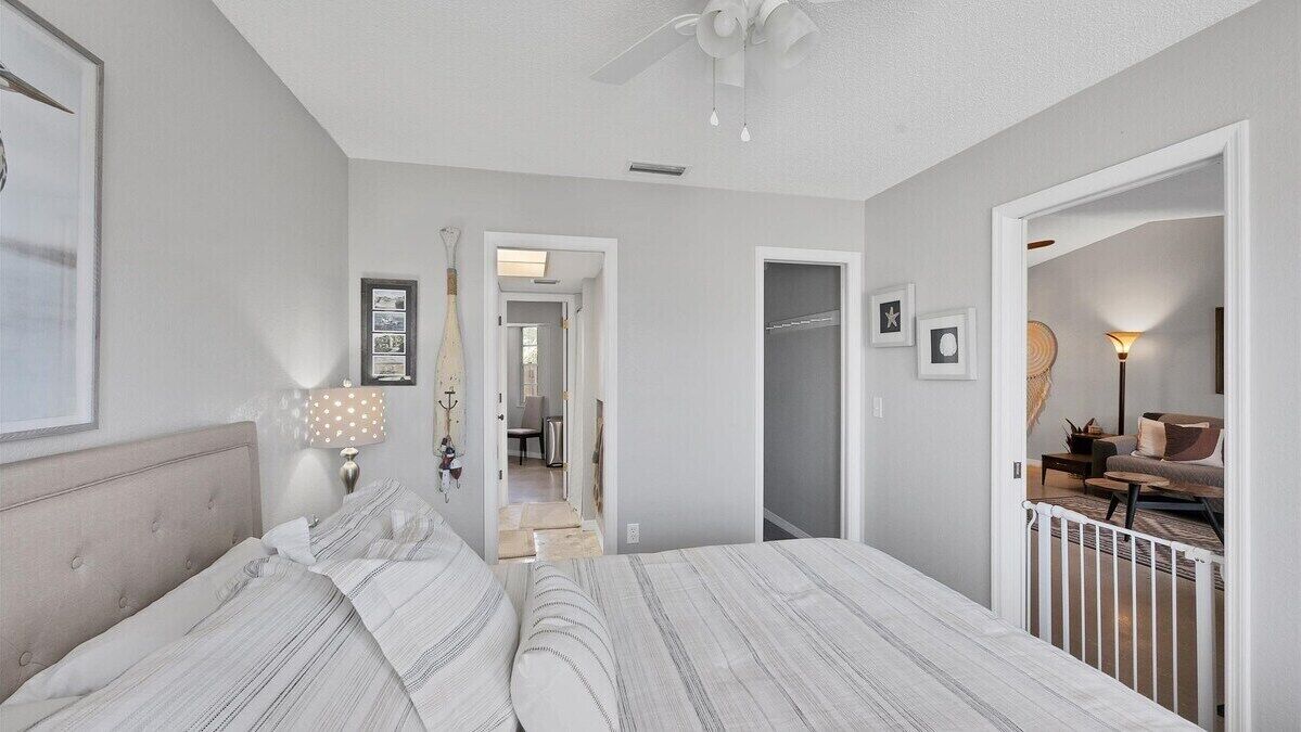A bedroom with a bed, a ceiling fan, a nightstand, and a lamp.