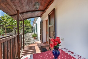 A covered outdoor area with a wooden ceiling, a potted plant, and a table with a polka dot tablecloth. - Il Grappolo – Rustic Studio in Elba Countryside (Portoferraio)