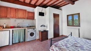Cozinha compacta com armários de madeira, máquina de lavar e radiador.