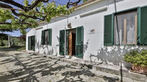 Um edifício branco com persianas verdes, uma escadaria de pedra e uma placa com a inscrição 