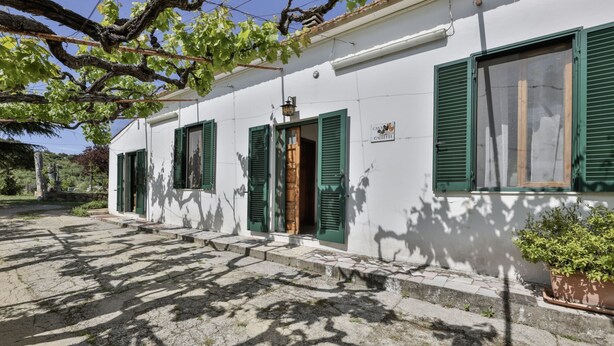 Un edificio blanco con contraventanas verdes, una escalera de piedra y un letrero que dice "CASA GALLETTI".
