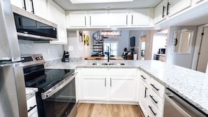 A modern kitchen with white cabinets, a black stove, and a granite countertop.