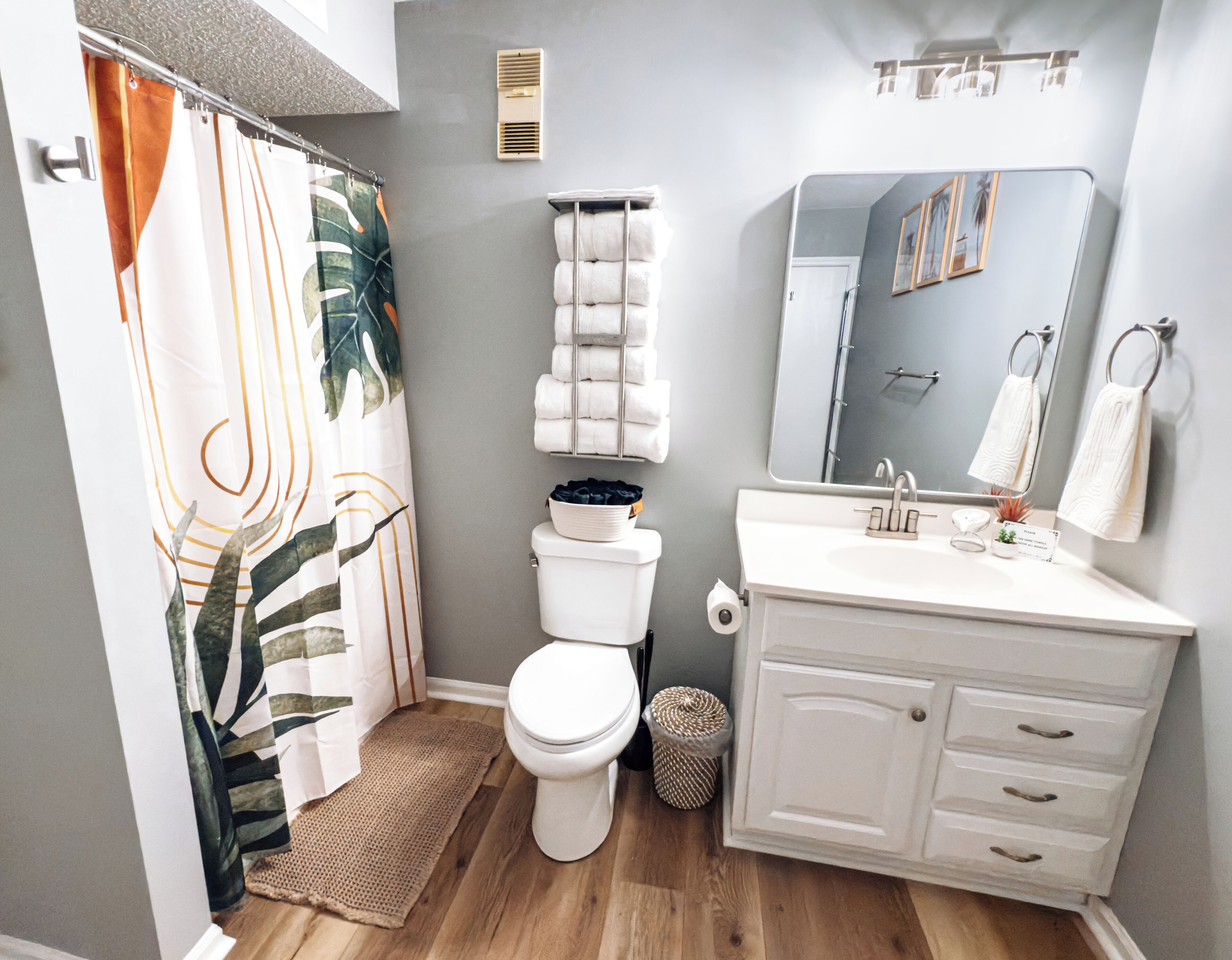 A bathroom with a toilet, sink, mirror, and shower curtain.