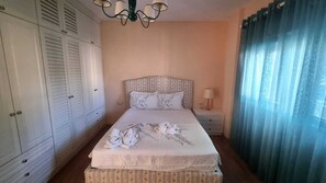 Ein Schlafzimmer mit Bett, Nachttisch, Kleiderschrank und einer Chandelier.