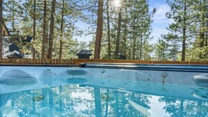 Ein klares Schwimmbecken mit einer Holzterrasse und Blick auf hohe Kiefern.