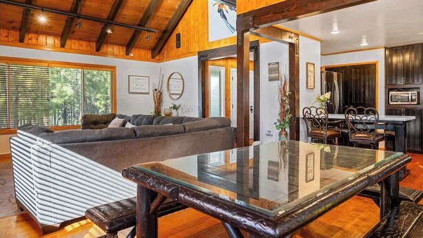 Ein modernes Interieur mit Holzboden, einem Glastisch, einer Sitzecke und einer Küchenzeile.