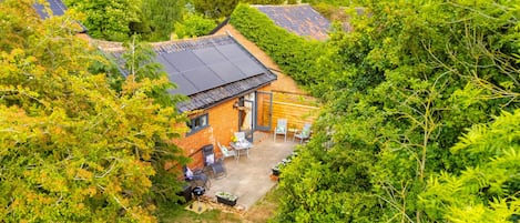 Escape to a serene retreat surrounded by lush greenery and mature trees, featuring a cozy patio and solar-powered charm.