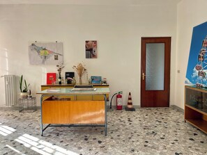 A reception desk with a map, a framed photo, and a fire extinguisher. - The Collector's House - View of the train station and park (Unknown)