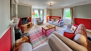 A living room with a sofa, armchairs, a coffee table, and a television.