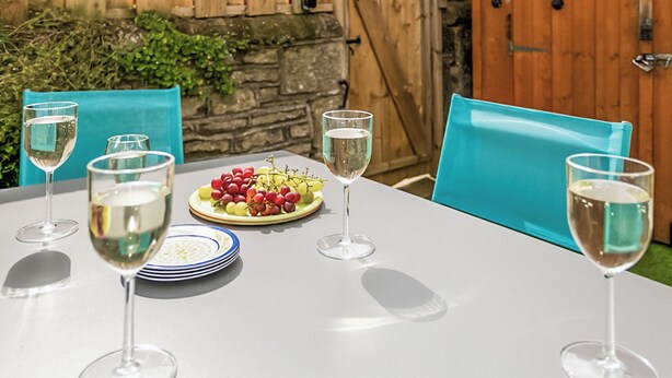 A table set for four with wine glasses, a plate of grapes, and a blue chair. - 3 bedroom accommodation in Skipton (Skipton)